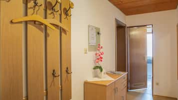 A hallway with wooden doors, a bulletin board, and a small cabinet with a vase of flowers.