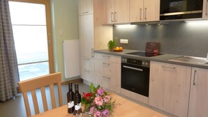 Eine moderne Küche mit Holzausstattung, einem eingebauten Backofen und einer Edelstahl-Dunstabzugshaube.