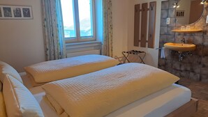 Ein Schlafzimmer mit zwei Betten, einem Fenster, einer Heizung, einem Spiegel, einem Waschbecken und einem Wäscheständer.