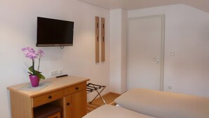 Ein Zimmer mit einem Bett, einem Schreibtisch mit Stuhl, einem Fernseher und einer Tür.