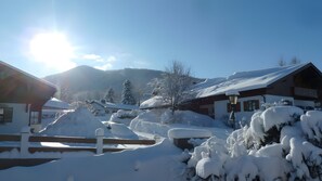 A snow-covered village with wooden buildings, a wooden fence, and mountains in the background. - Apartment “Anna” with Mountain View, Shared Terrace, and Wi-Fi (Bad Kohlgrub)