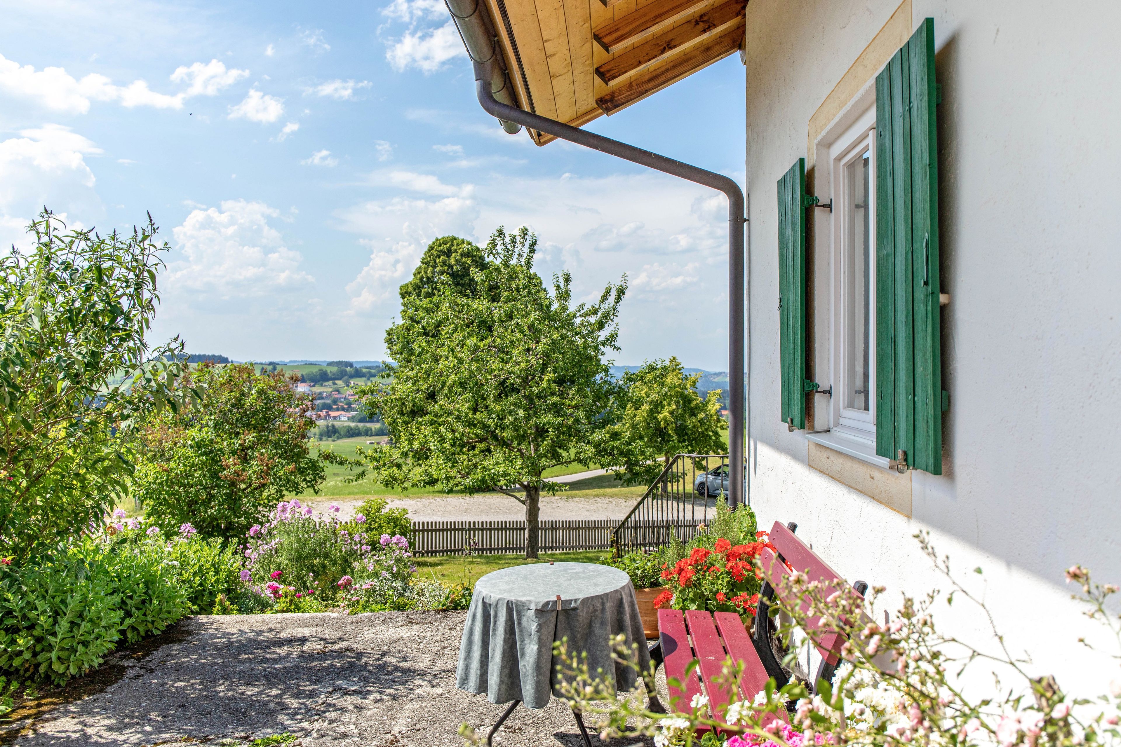 Un patio con tavolo, panchina e vista su un albero e il paesaggio.