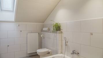 Ein Badezimmer mit Toilette, Dusche und Heizkörper.
