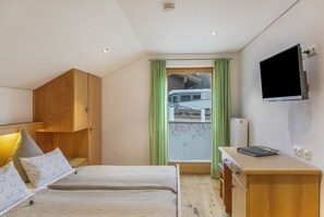 Un dormitori amb dos llits, un armari de fusta, un escriptori amb televisió de pantalla plana i una finestra que mostra una autocaravana.