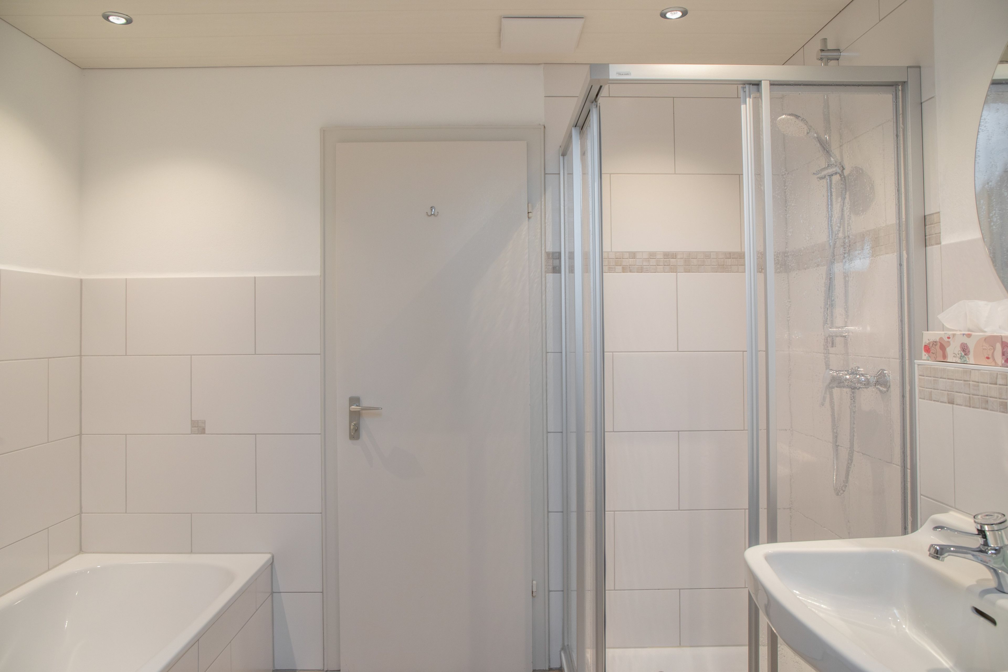 Un baño con ducha envuelta en vidrio, bañera y lavabo.