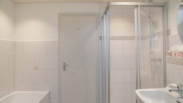 Un baño con ducha envuelta en vidrio, bañera y lavabo.