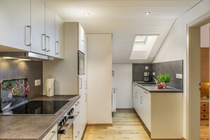 Una cuina moderna amb una illa central, forn integrat i un lucernari.