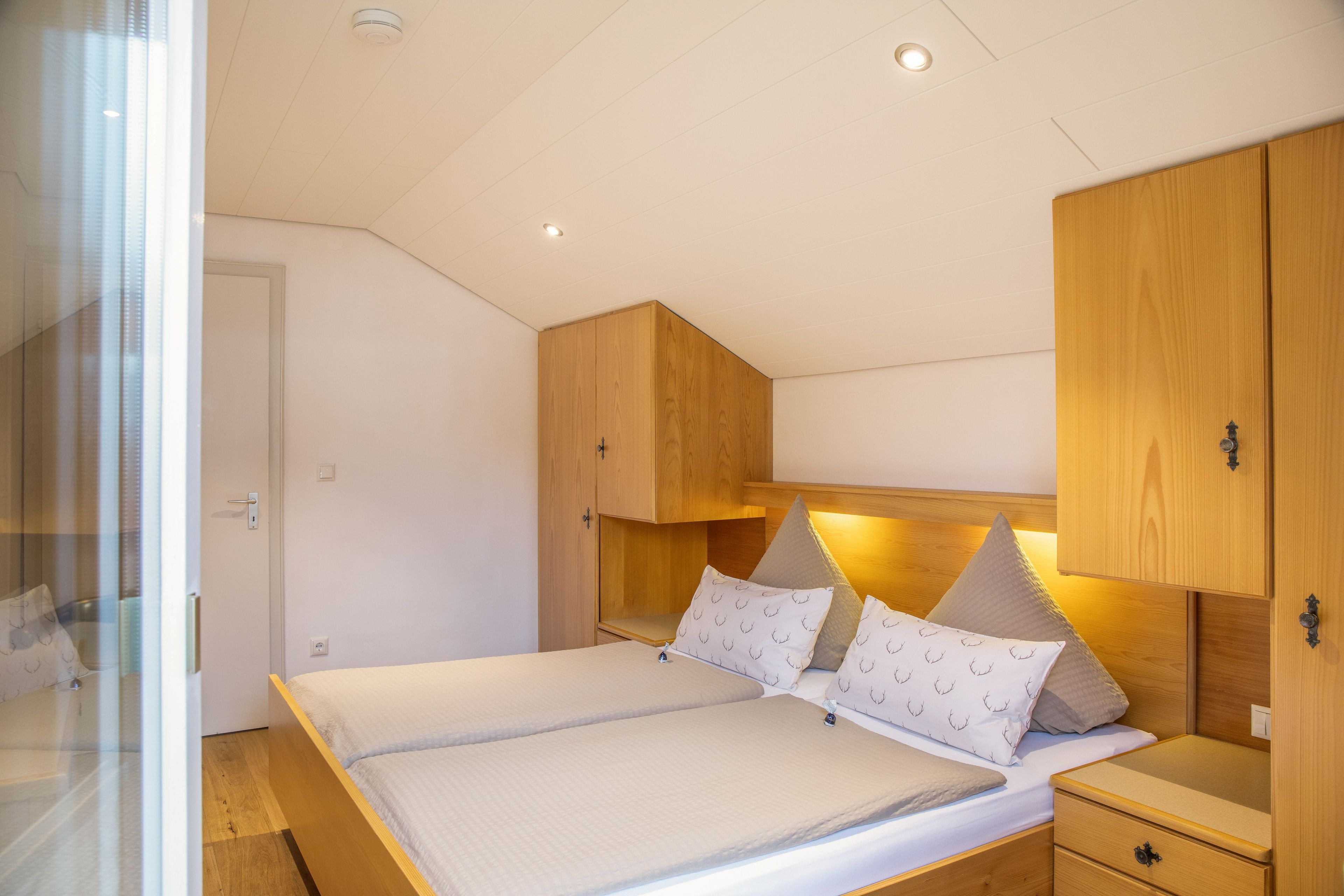 A bedroom with a bed, bedside tables, and wooden cabinets.
