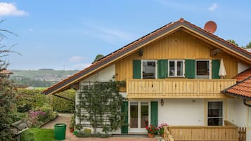 Ett tvåvåningshus med en balkong, en trädgård och utsikt över landsbygden.