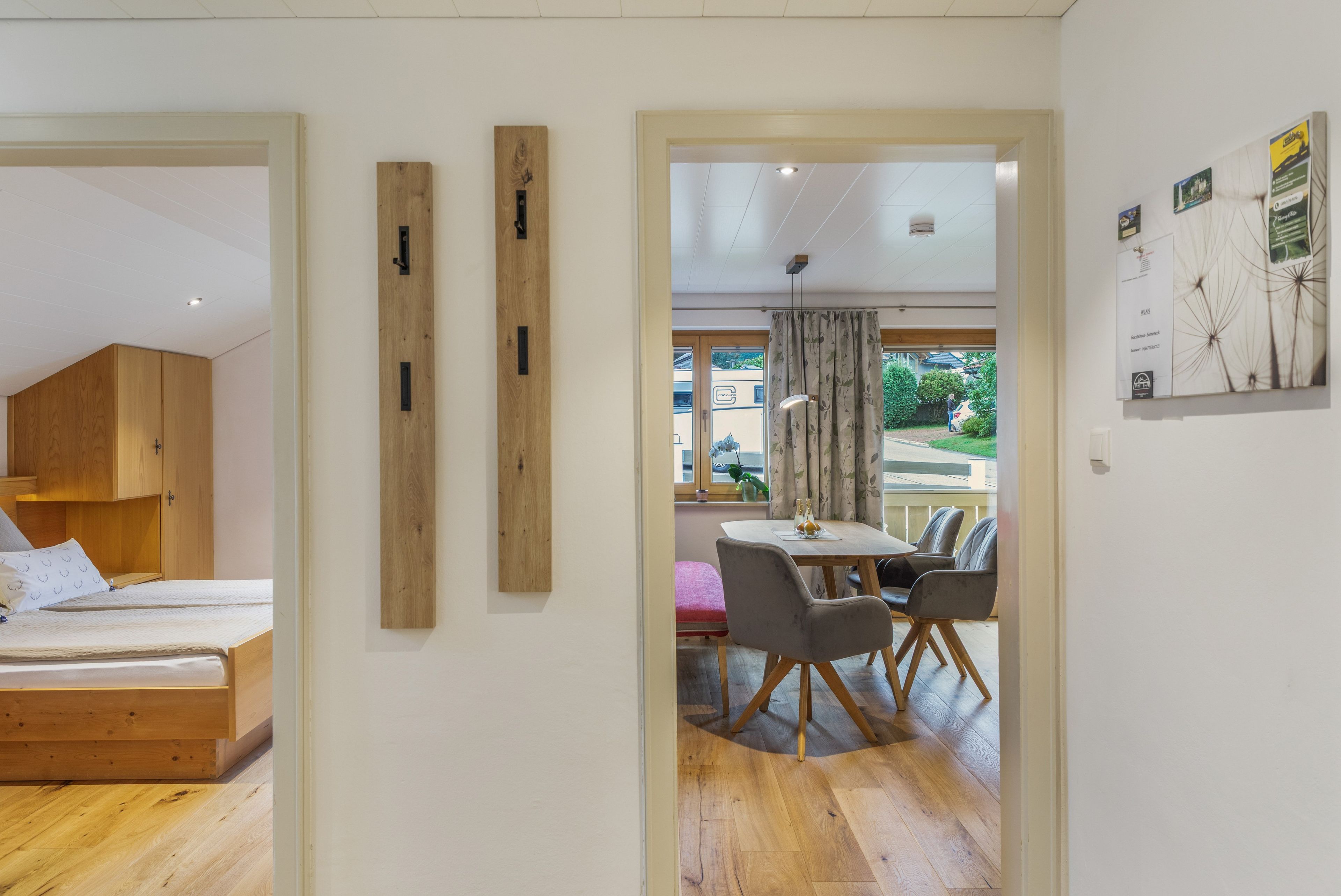 Una habitación moderna con una cama, un armario de madera y una zona de comedor con mesa y sillas.