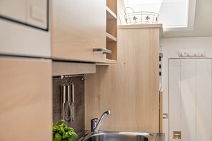 A kitchen with wooden cabinets, a stainless steel sink, and a hanging utensil rack.
