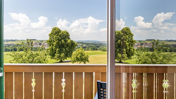 Een balkon met uitzicht op een groen landschap en bomen.