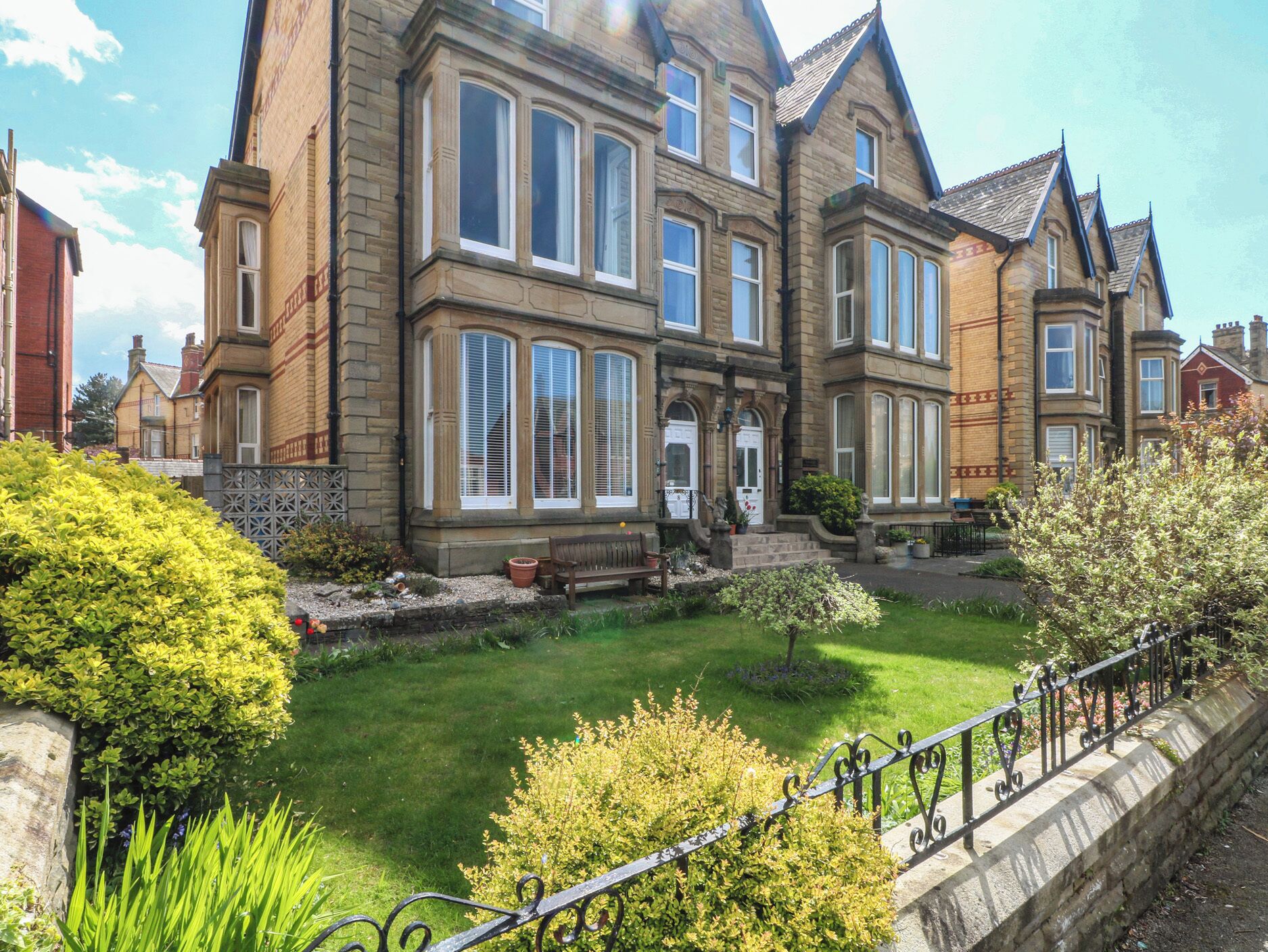 A large, historic building with multiple windows and a well-maintained garden.