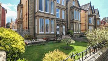 A large, historic building with multiple windows and a well-maintained garden.