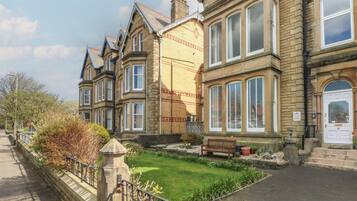 A row of traditional stone buildings with large windows and a small lawn area.