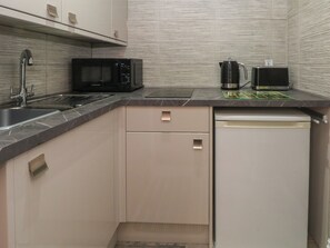 A compact kitchen with a microwave, coffee maker, and dishwasher. - Apartment 4 (Lytham St. Anne's)