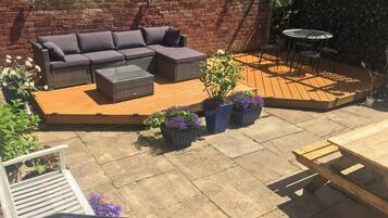 A patio with a sofa, planters, and a table.
