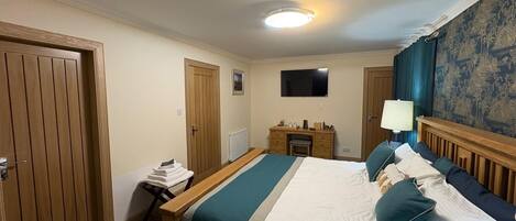 A hotel room with a bed, a desk, a chair, a television, and a window with curtains.