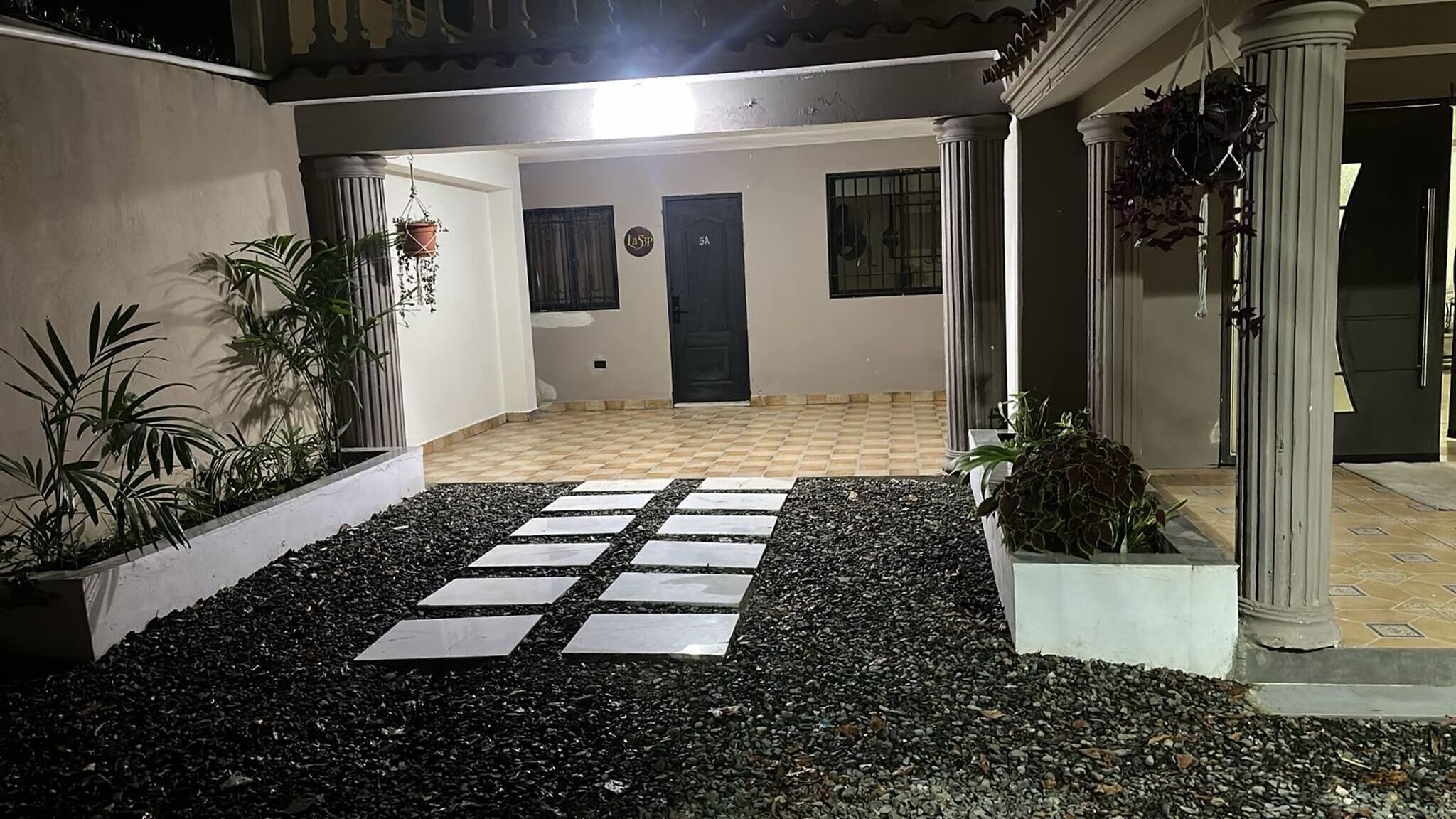 A courtyard with a tiled floor, a black door, and potted plants.