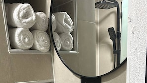 A bathroom with a white sink, a mirror, and a towel rack with rolled towels. - Room-las3p Acogedor Apartamento Cerca de (Santo Domingo)