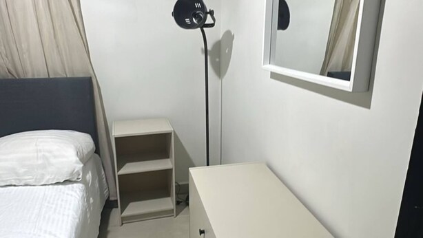A bedroom with a bed, a desk, a mirror, and a floor lamp. - Room-las3p Acogedor Apartamento Cerca de (Santo Domingo)