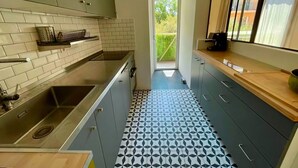 Een moderne keuken met een ingebouwde kookplaat, een spoelbak en een aanrecht. Er is een raam dat natuurlijk licht binnenlaat en uitzicht biedt op groen.