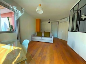 Ein modernes Wohnzimmer mit einem weißen Sofa, einem Glastisch und Holzboden.