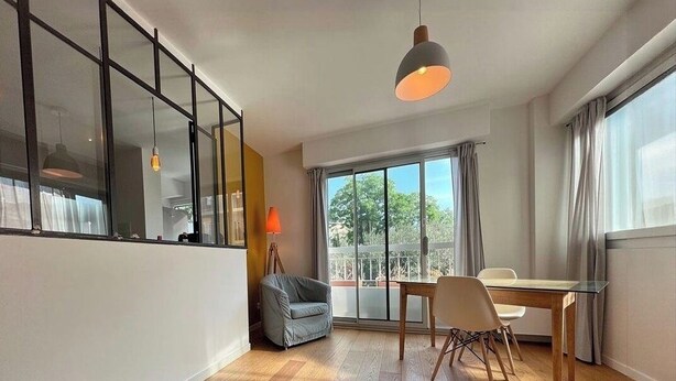 Een moderne kamer met een glazen wand, een eettafel, stoelen, een lamp en een hanglamp.