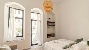 Une chambre avec un lit, un canapé, un luminaire suspendu et une vue par la fenêtre.