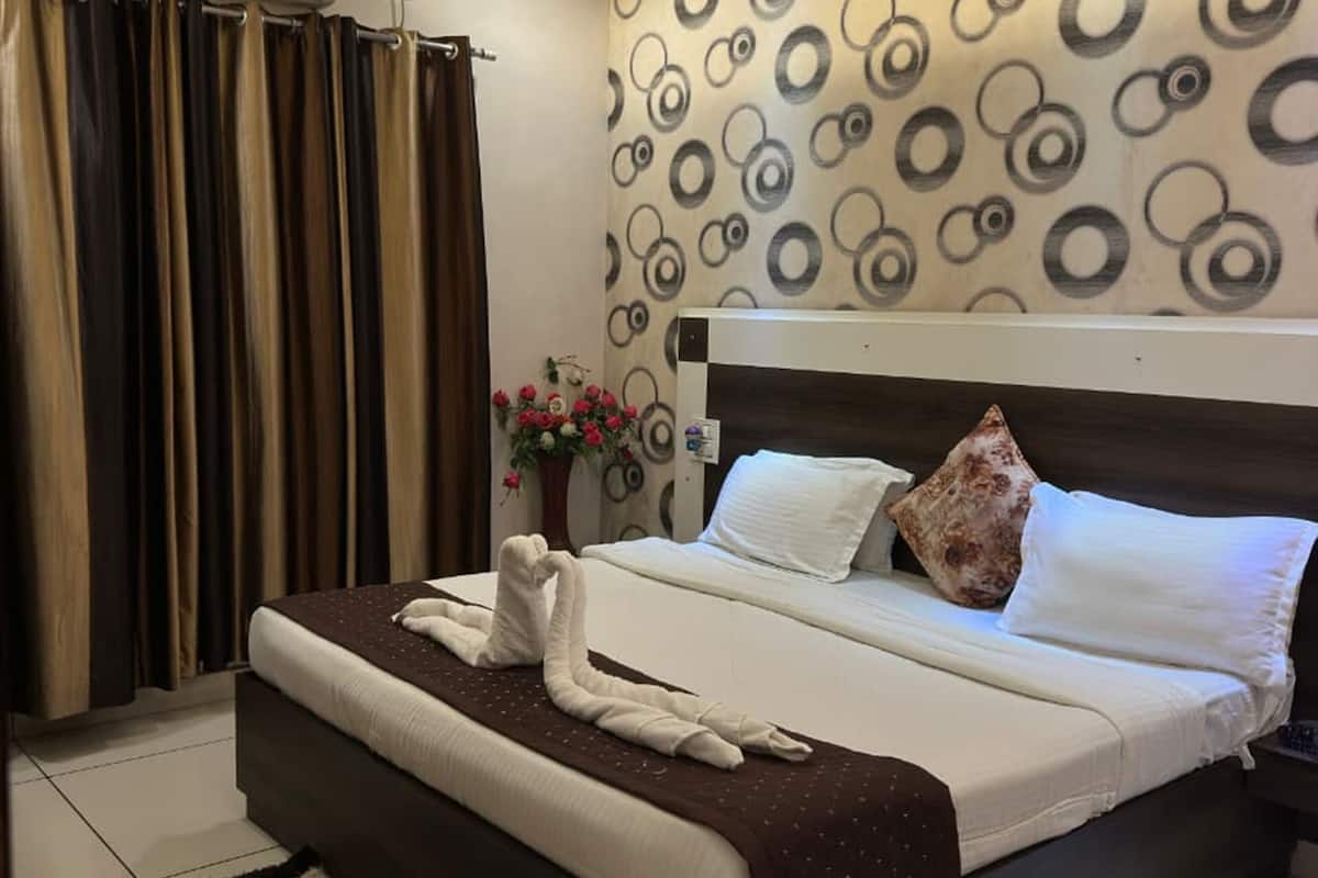 A hotel room with a bed, a ceiling fan, a patterned wall, and a potted plant.