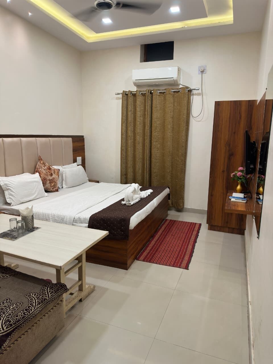 A hotel room with a bed, bedside table, and a small desk.