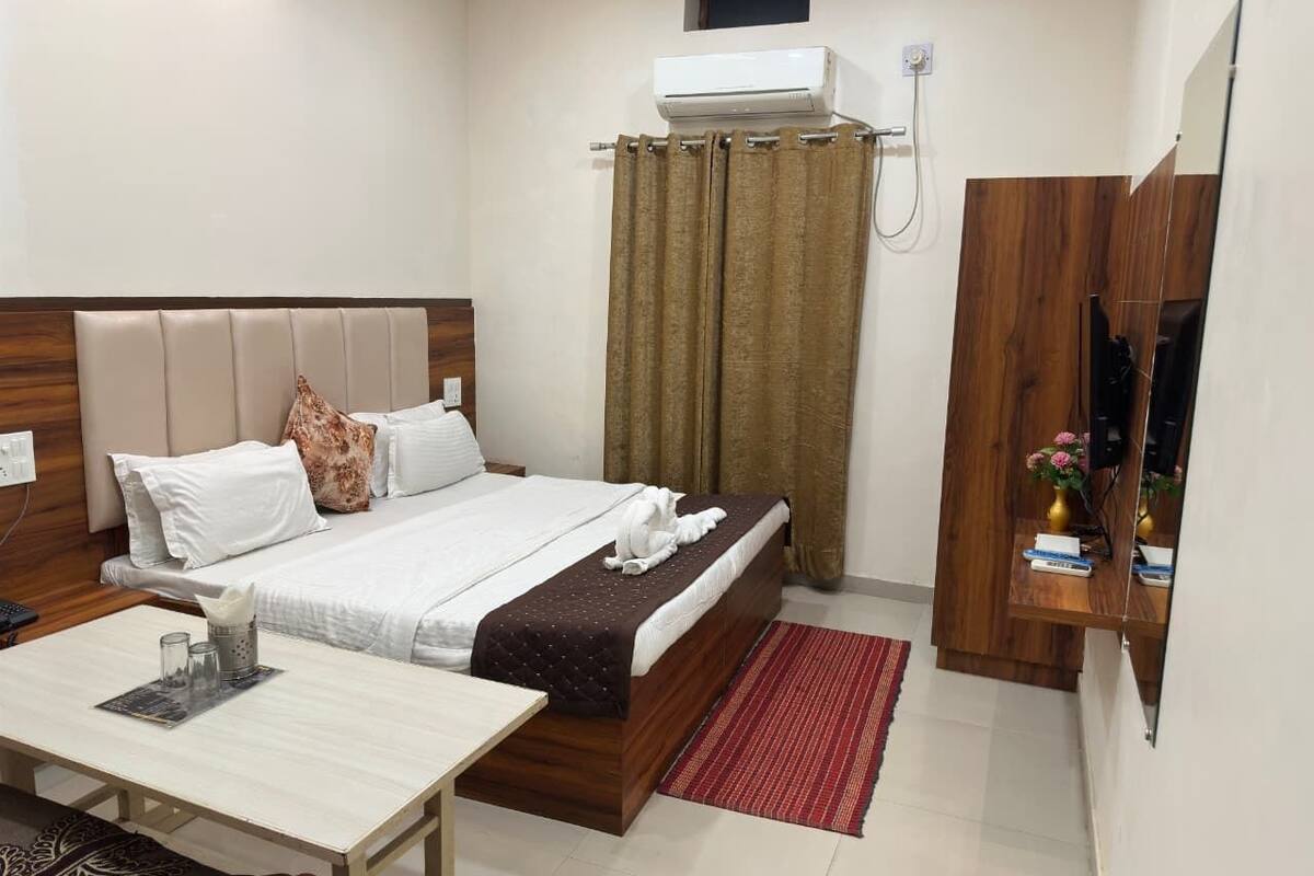 A hotel room with a bed, a desk, a TV, and a shower area.