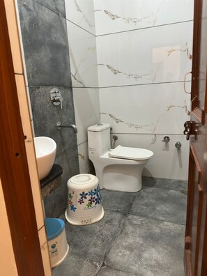 A bathroom with a toilet, sink, and a trash bin.