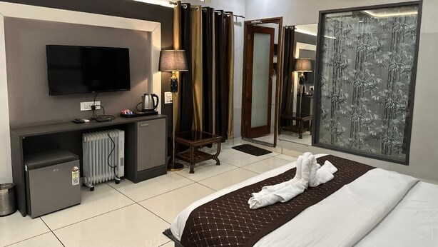 A hotel room with a bed, a desk with a computer, a television, a mirror, and a window with a view.