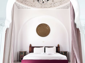 Un dormitorio con cama, dos mesitas de noche, un techo decorativo y un cuadro colgado en la pared.