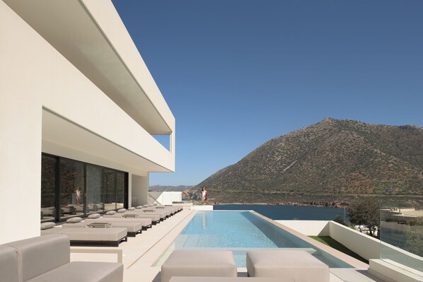 A modern pool area with a view of a mountain and a body of water.