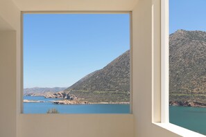 Una habitación con ventana que ofrece vistas a un lago y montañas.