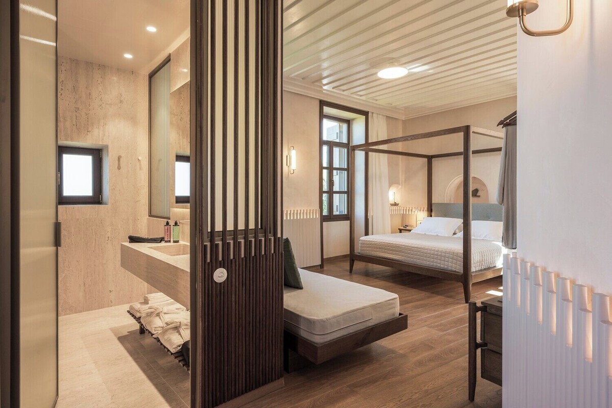 Quarto moderno com cama de dossel, sofá independente, escrivaninha embutida e um espelho grande.