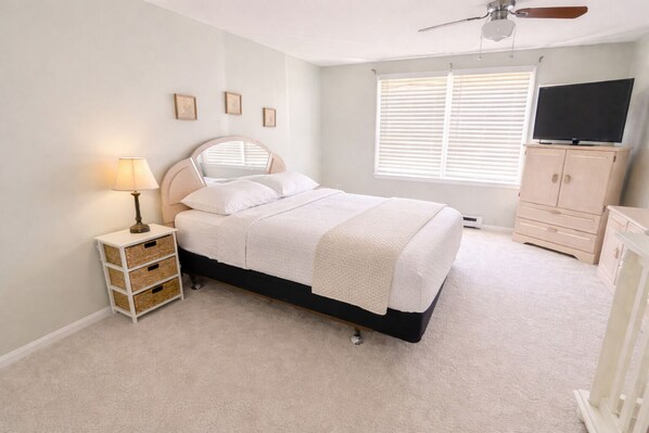 A bright bedroom with a mirrored headboard, large window, and TV console. - North OC Townhouse Walk to Beach, 2 Parking (Ocean City)