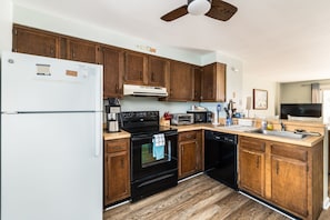 Kitchen with wooden cabinetry, black appliances, and a white refrigerator. - North OC Townhouse Walk to Beach, 2 Parking (Ocean City)