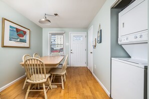 Dining area with table and chairs adjacent to an entry door and stacked laundry unit. - North OC Townhouse Walk to Beach, 2 Parking (Ocean City)