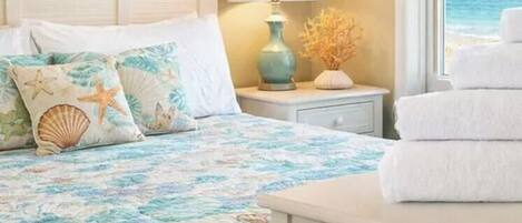 A coastal-themed bedroom with ocean views and folded white towels.