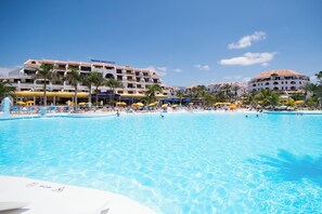 A hotel with a large pool, multiple balconies, and palm trees. - Parque Santiago III 222 - One Bed (Playa de las Américas)