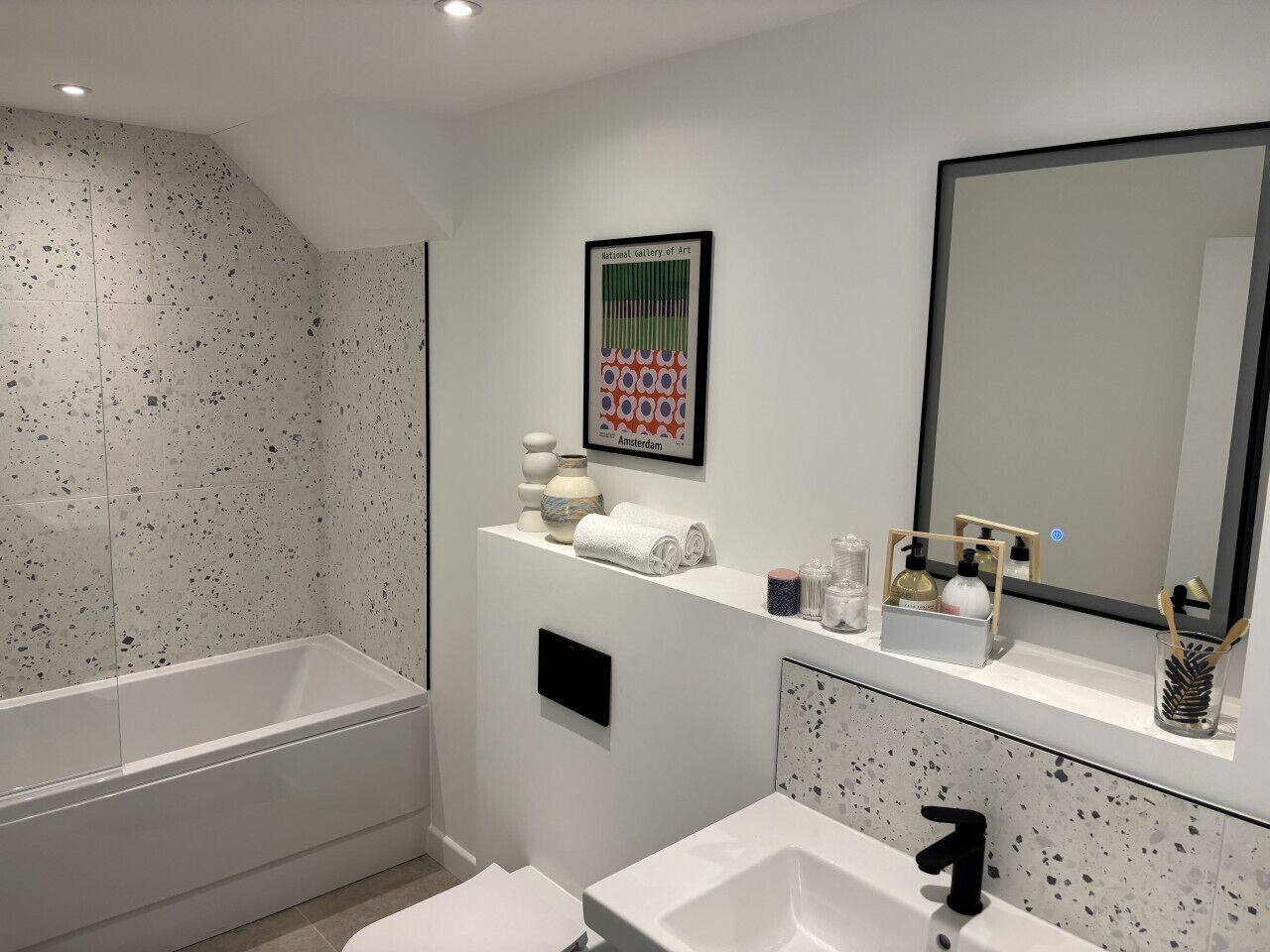 A modern bathroom with a freestanding bathtub, a large mirror, and a sink with a black faucet.