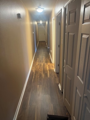 A hallway with wooden flooring, white walls, and closed doors. - Entire townhouse in New Orleans, Louisiana. (New Orleans)