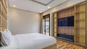 Un dormitorio con una cama grande, televisor y puerta corrediza de vidrio que da a un balcón.