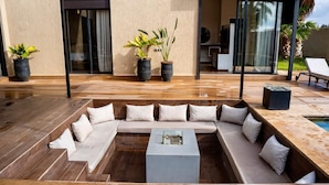 Un espacio exterior moderno con una zona de estar modular, una mesa de centro y plantas en macetas.