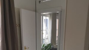 A hallway with a glass door leading to a living area with a plant and a sofa. - Spacious Quadruple Room w. Private Bathroom (Brugge)