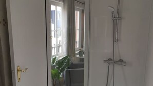 A modern bathroom with a glass shower enclosure, a potted plant, and a view of a balcony. - Spacious Quadruple Room w. Private Bathroom (Brugge)