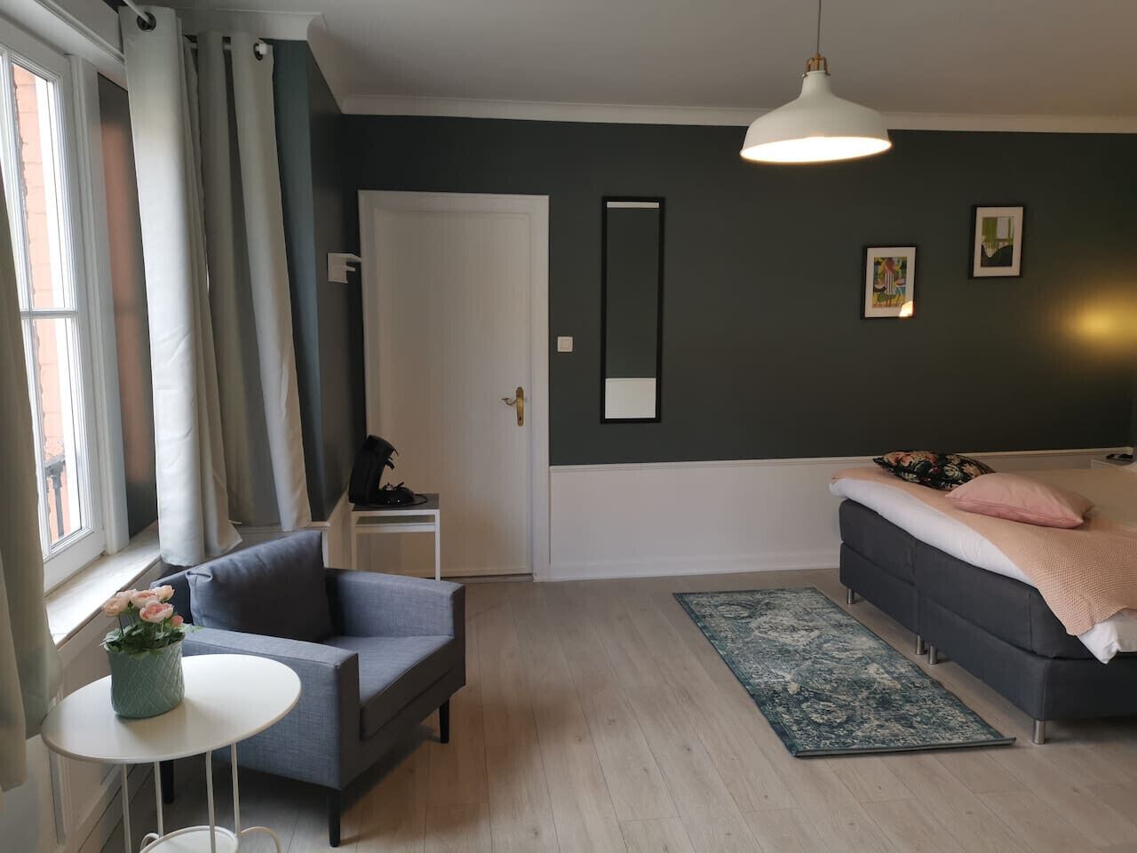 Une chambre à coucher moderne avec un lit, un canapé, une petite table ornée de fleurs, un miroir et une porte.